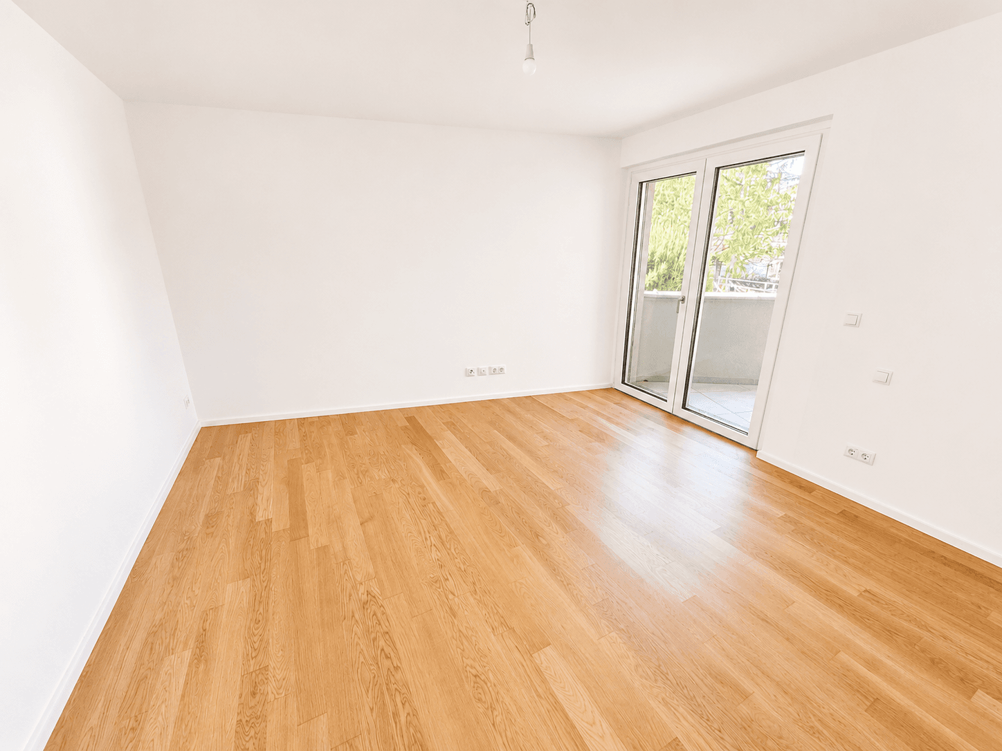 Lichtdurchflutetes Schlafzimmer mit Eichenparkett und Zugang zu einem kleinen Balkon.