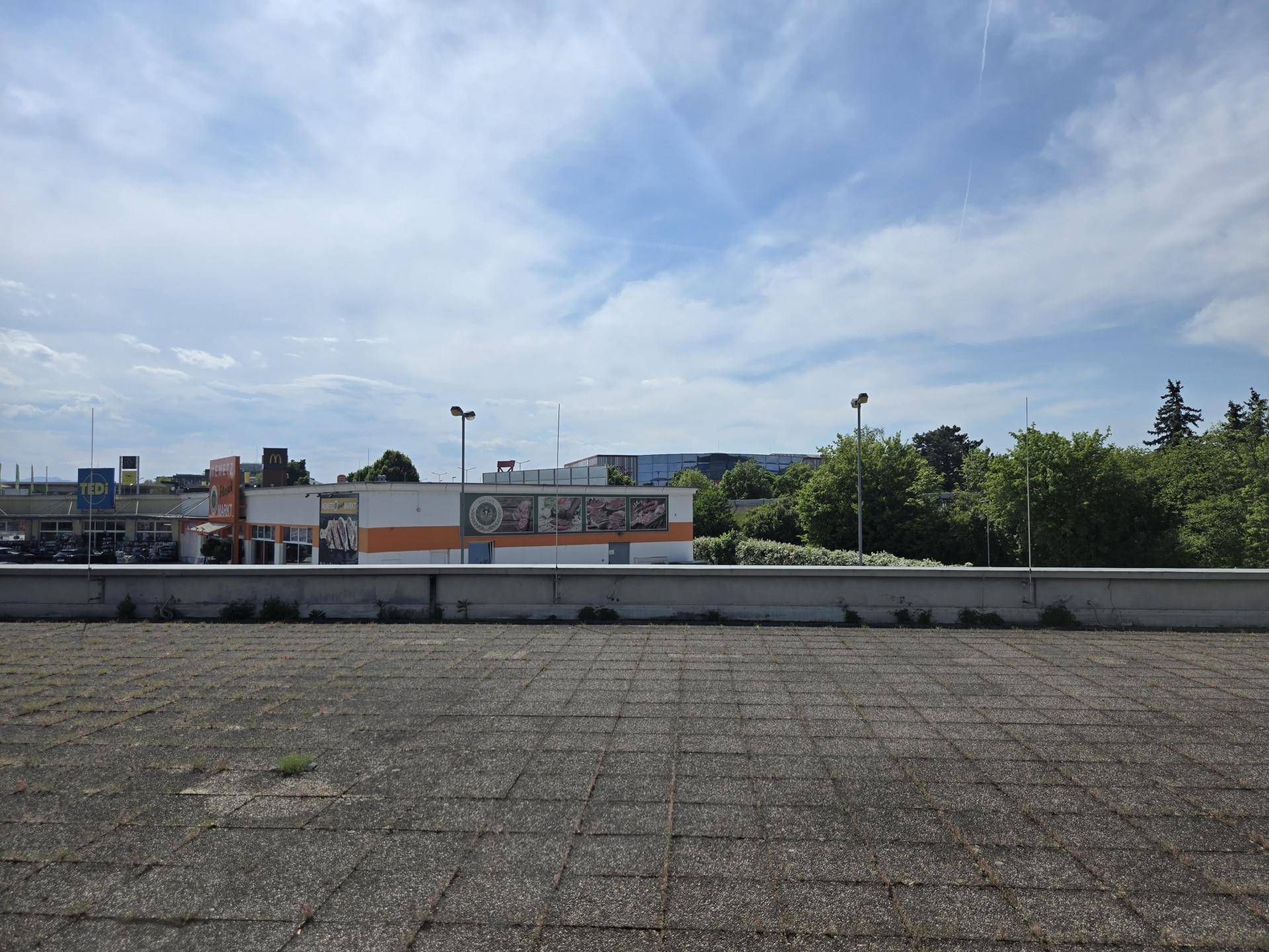 Blick von einem Dach auf umliegende Gebäude und den Himmel mit Wolken.