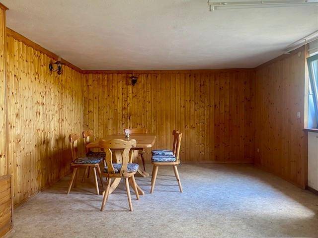Esszimmer mit holzvertäfelten Wänden und einem traditionellen Esstisch mit Stühlen.