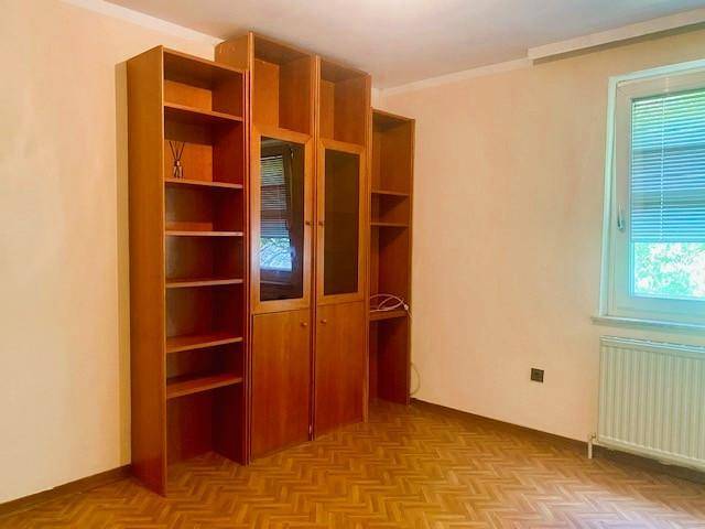 Zimmer mit eingebauten Holzregalen und Schränken, ideal als Schlafzimmer oder Arbeitszimmer nutzbar.