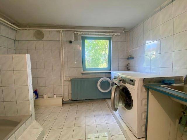 Hauswirtschaftsraum mit Waschmaschine, Spülbecken und gefliesten Wänden, ideal für Wäschepflege.