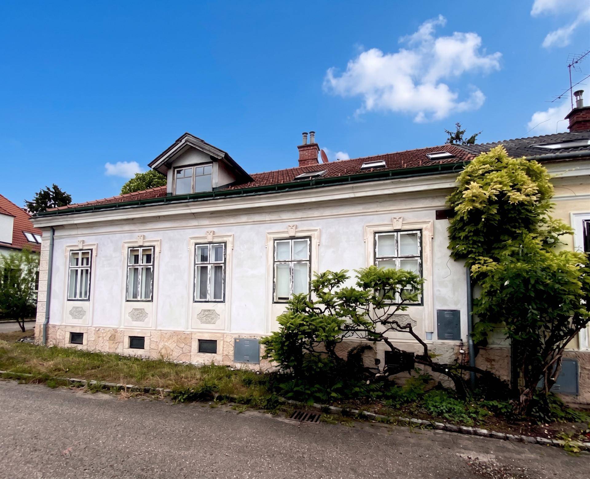 Historisches Gebäude mit heller Fassade, roten Dachziegeln und gepflegter Umgebung.