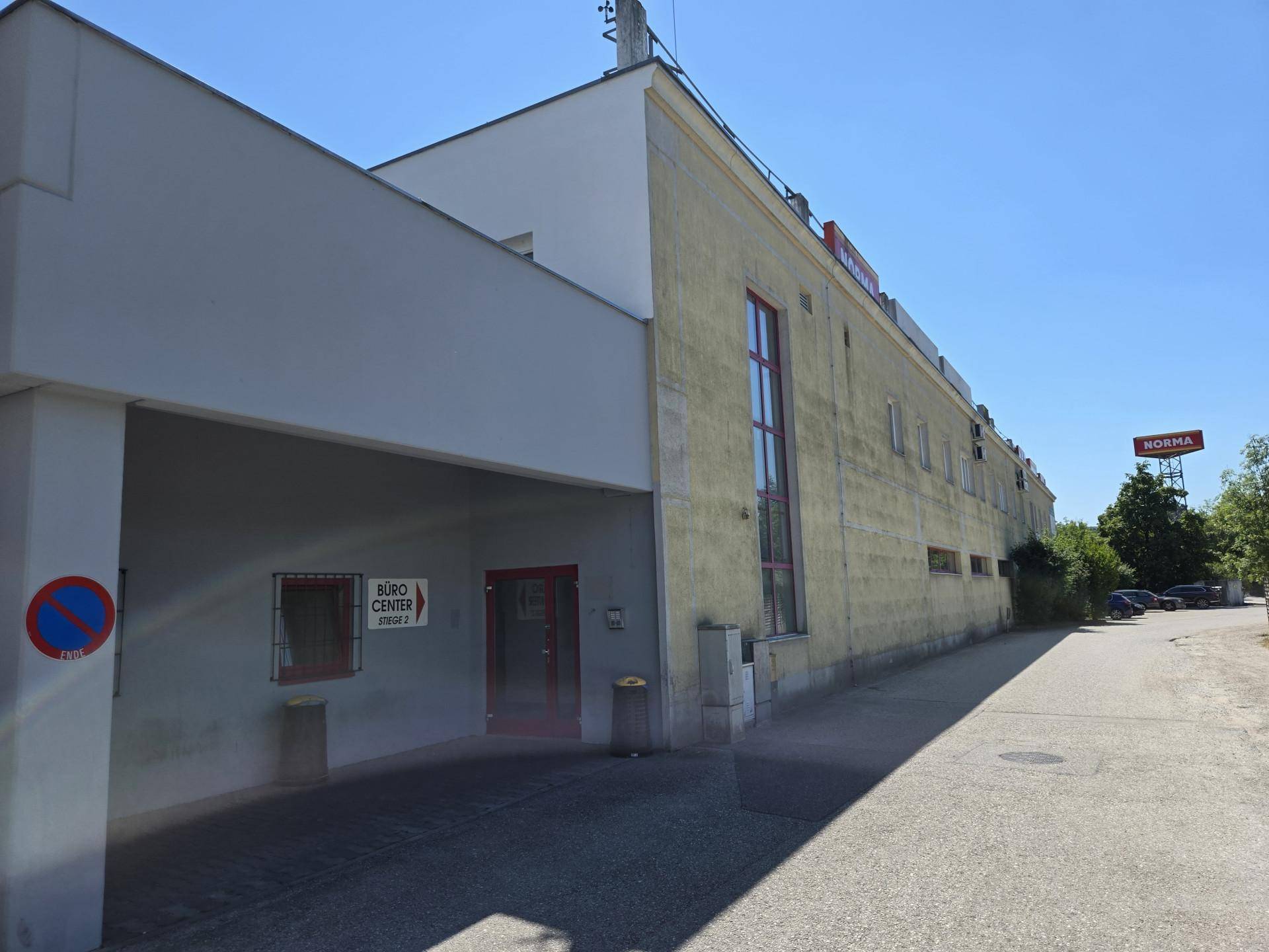 Seitenansicht des Geschäftshauses mit dem Eingang zum Bürocenter und einem Parkverbotsschild.