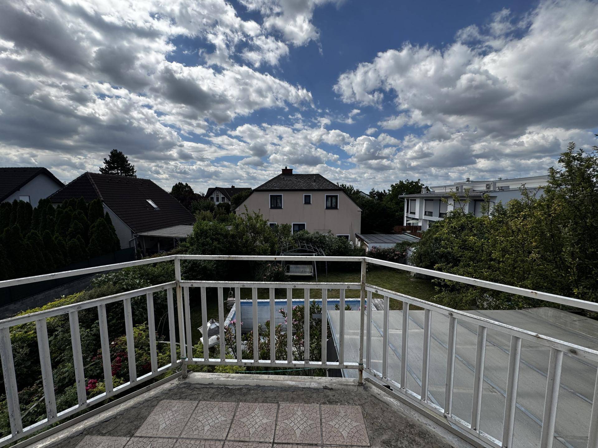 Balkon mit weitem Blick über die Nachbarschaft und den Garten mit Pool.