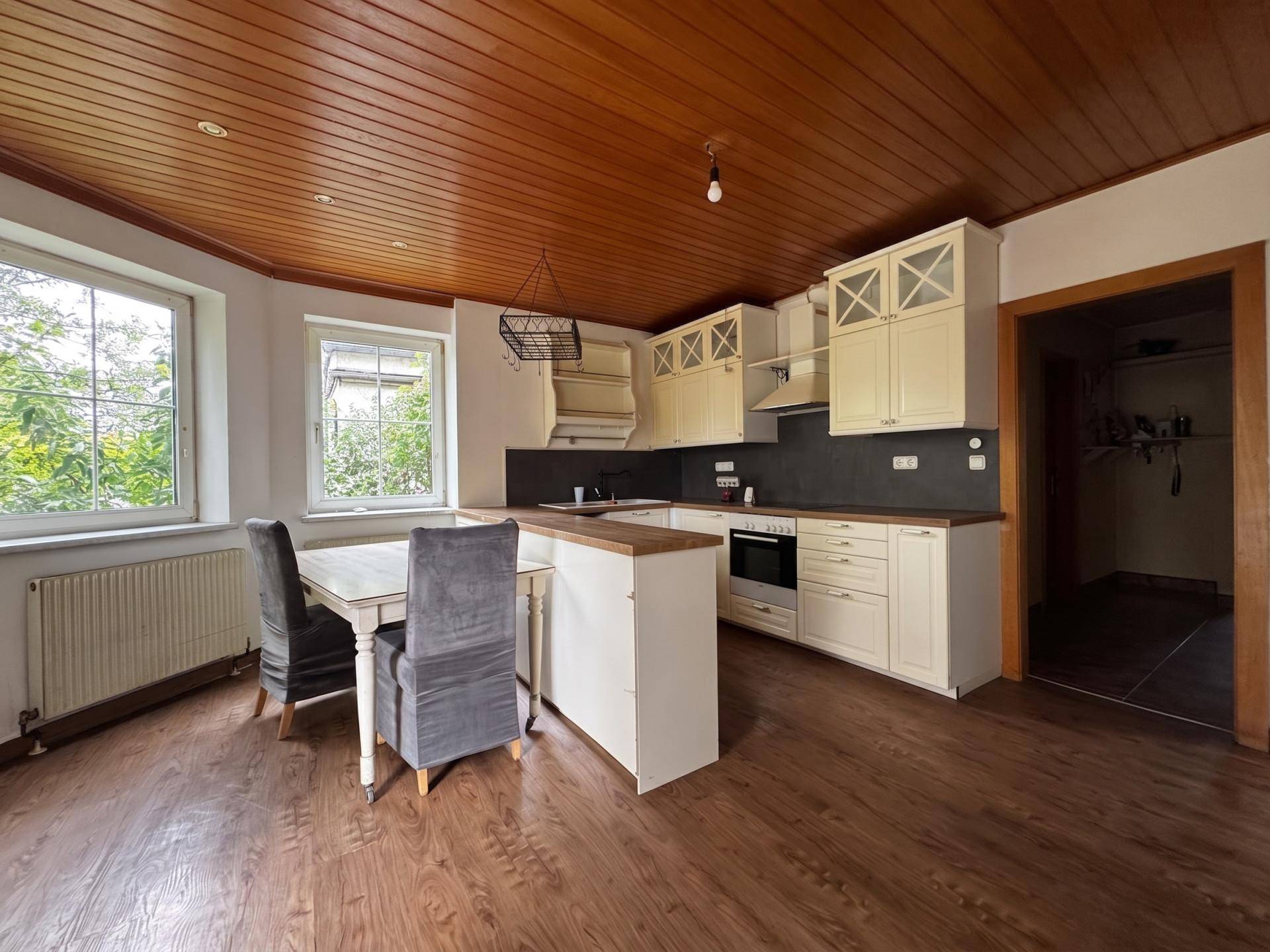 Helle Küche mit Holzbalkendecke, Essbereich und cremefarbenen Einbauschränken.