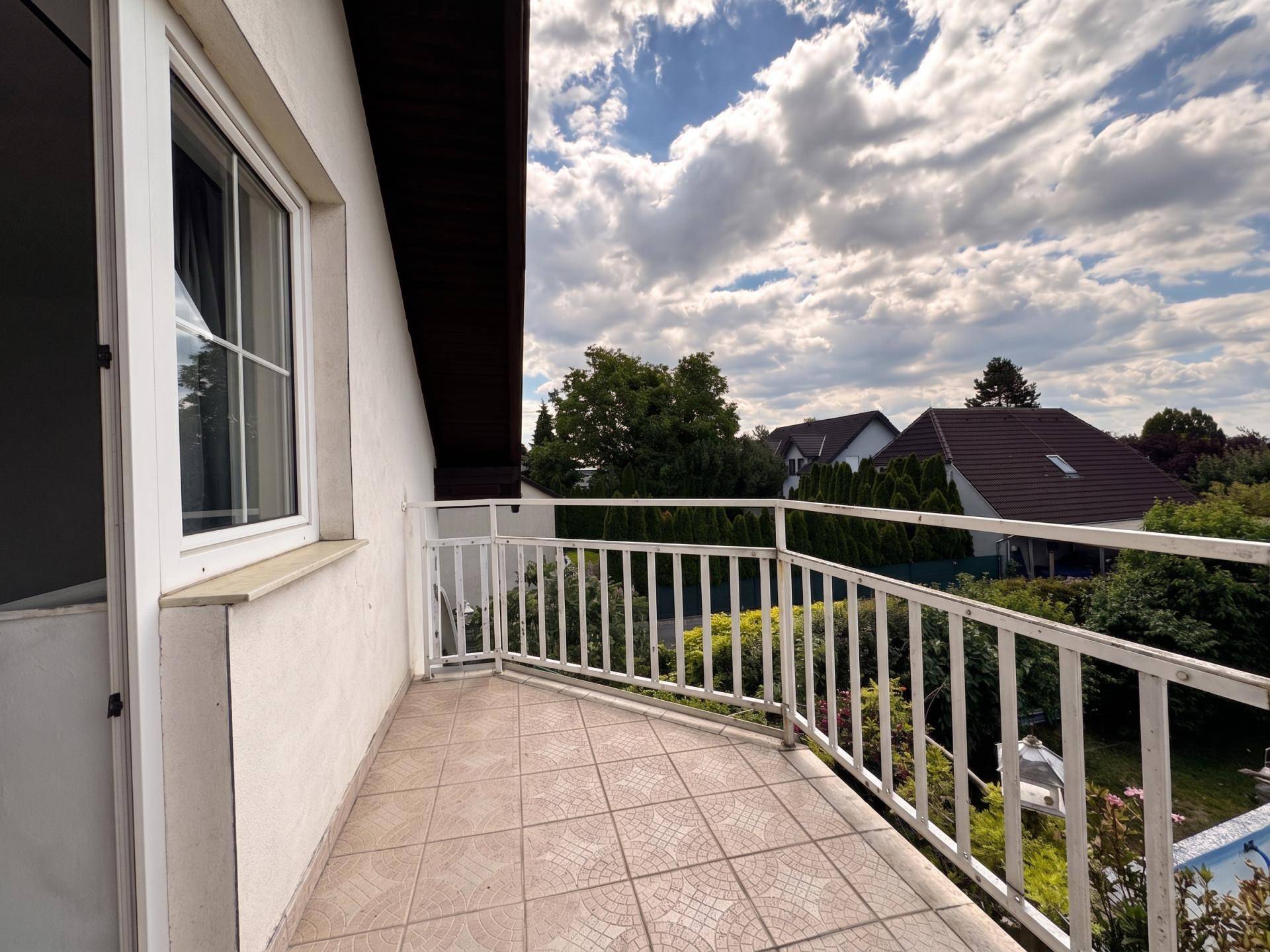 Kleiner Balkon mit Fliesenboden und weißem Geländer, bietet Blick ins Grüne.