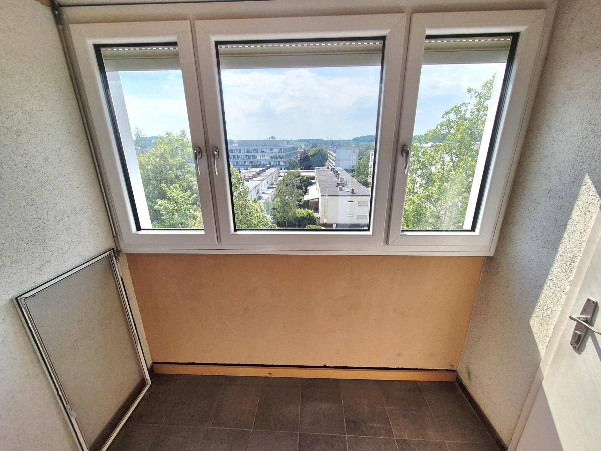 Verglaste Loggia mit weitem Blick auf die umliegenden Gebäude und Grünflächen.