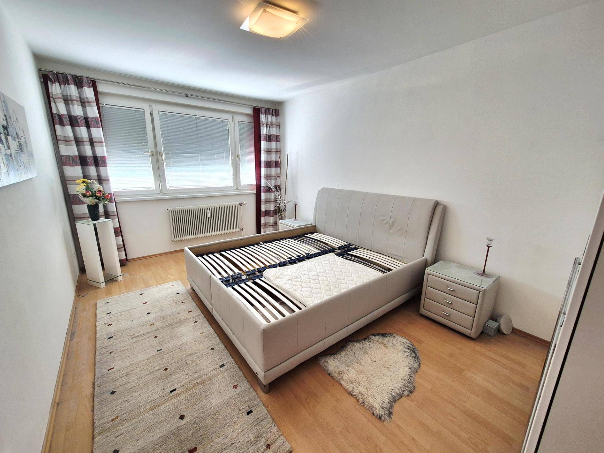 Helles Schlafzimmer mit Doppelbett, Nachttischen und Holzparkettboden.
