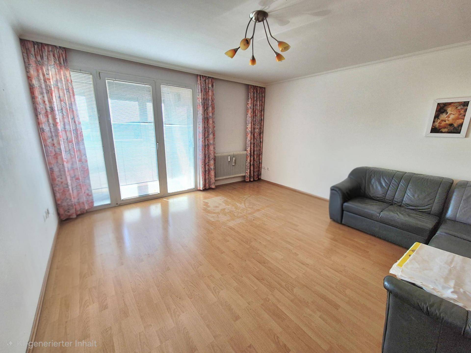 Geräumiges Wohnzimmer mit Ledersofa, Holzparkettboden und Zugang zum Balkon.