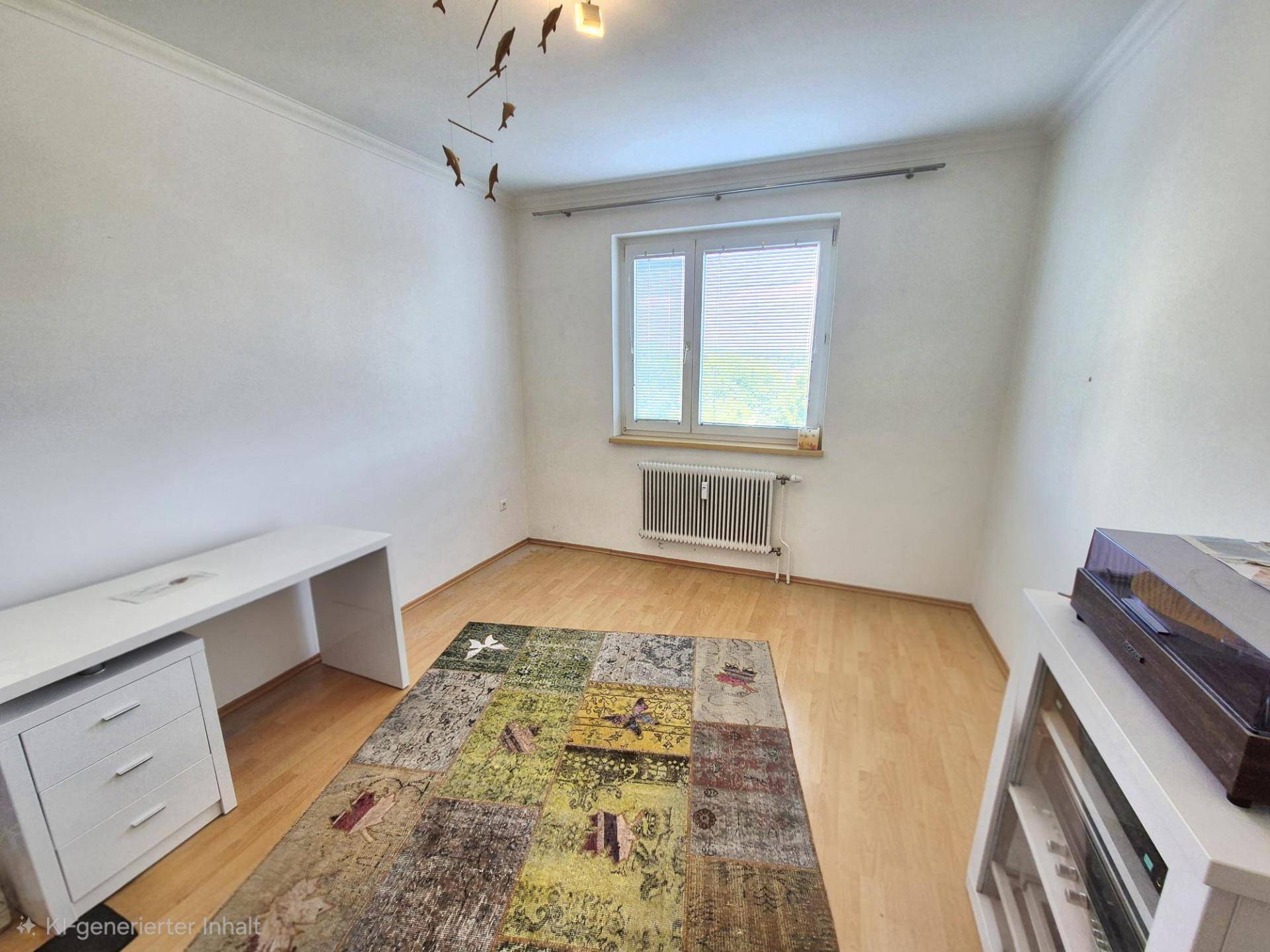 Helles Zimmer mit Schreibtisch, Holzparkettboden und großem Fenster.