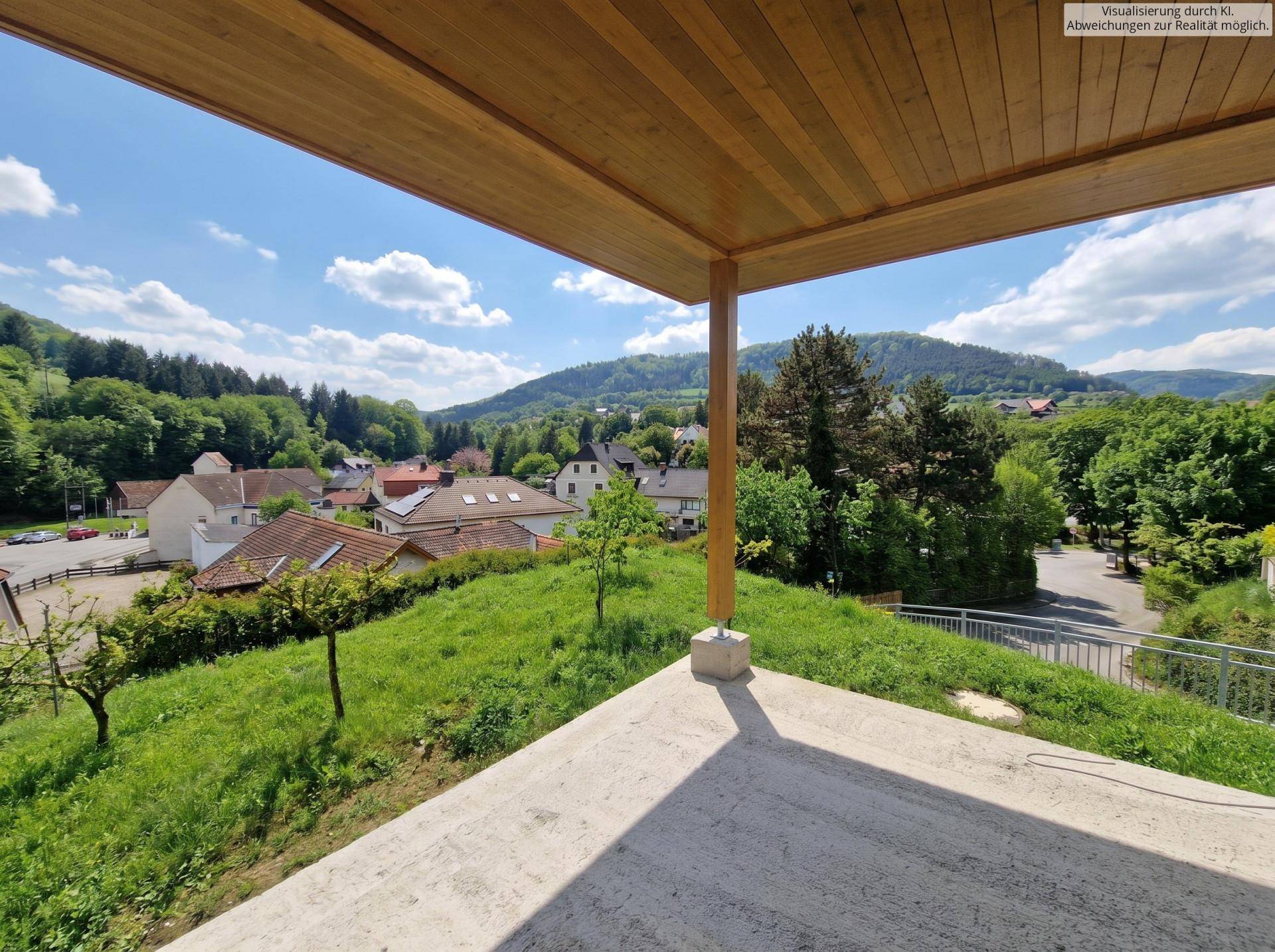 Sonnige überdachte Terrasse mit weitem Blick über das Tal und die bewaldeten Hügel unter blauem Himmel.