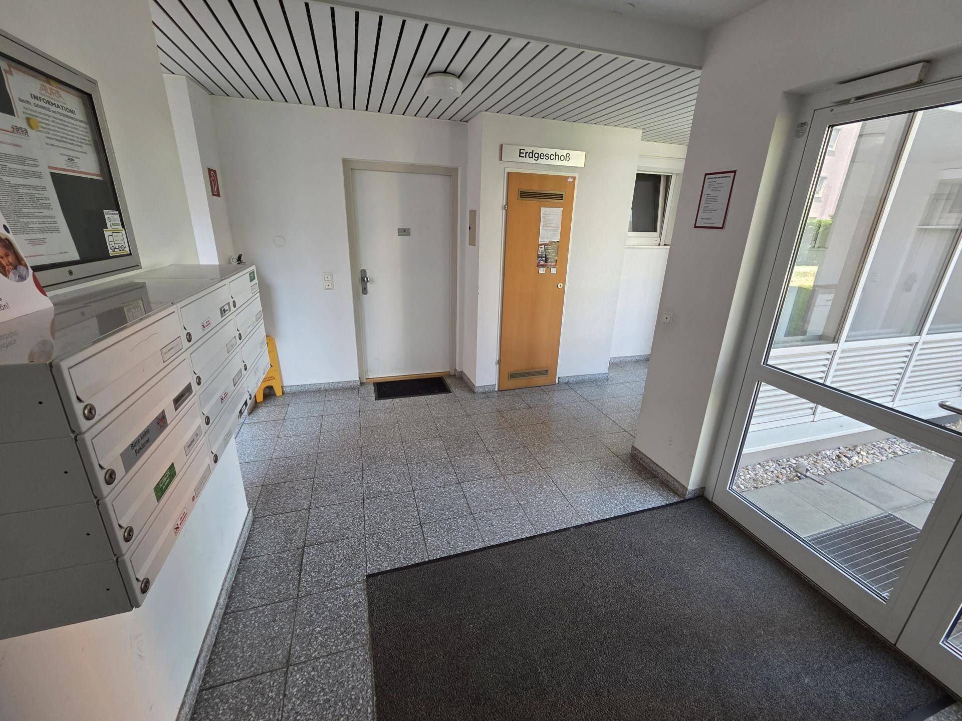 Eingangsbereich eines Mehrfamilienhauses mit Briefkästen und Zugang zum Erdgeschoss.