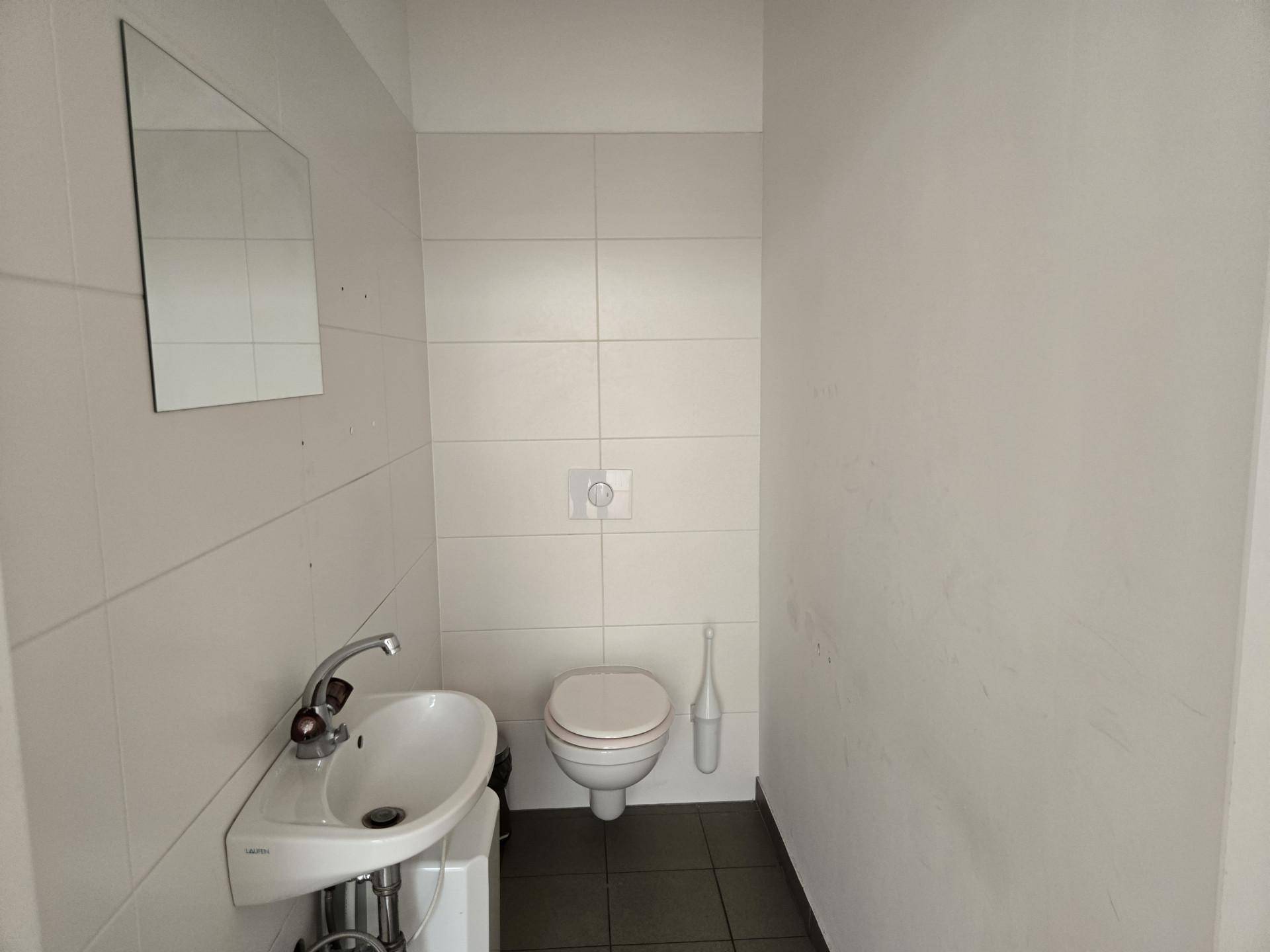 Modernes Gäste-WC mit wandhängender Toilette, kleinem Waschbecken und Fliesen an Wänden und Boden.