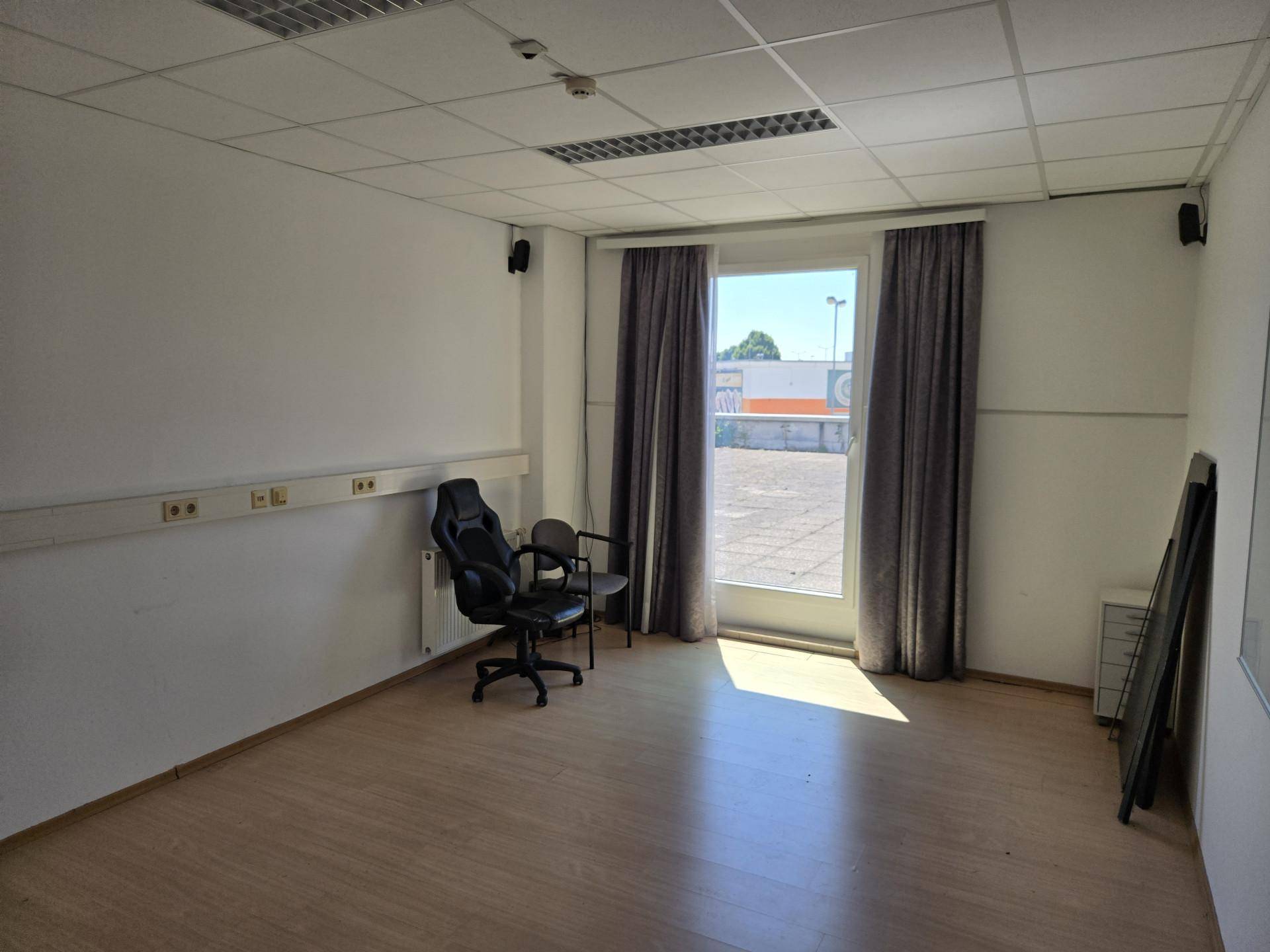 Büroraum mit Laminatboden, großem Fenster und Vorhängen, ideal für Besprechungen.