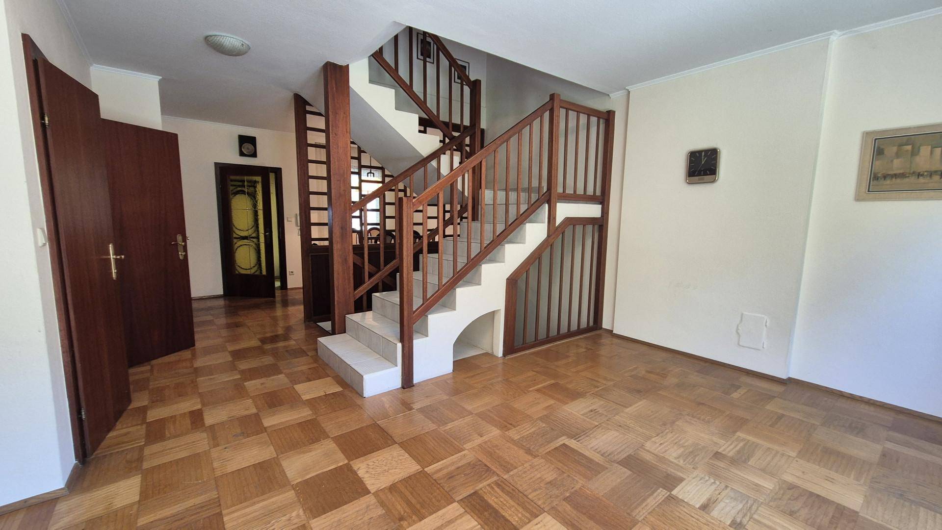 Geräumiger Flur mit Holztreppe und Parkettboden, der die verschiedenen Ebenen verbindet.