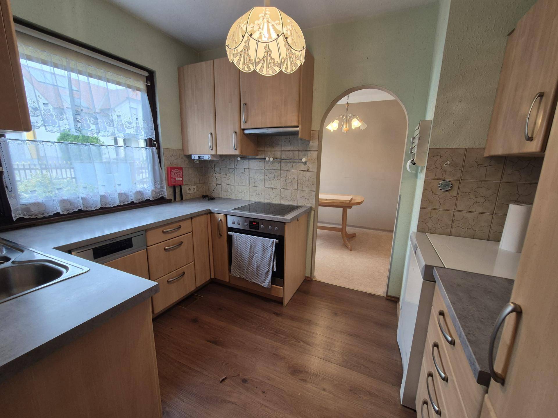 Funktionale Küche mit hellen Holzschränken, Einbaugeräten und Blick ins Esszimmer.