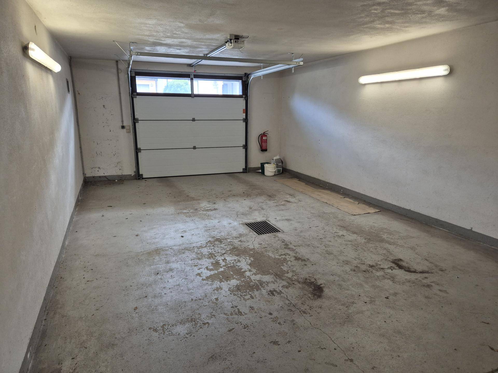 Geräumige Garage mit Betonboden, Rolltor und ausreichend Platz für ein Fahrzeug.