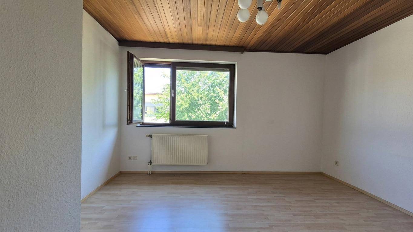 Helles Schlafzimmer mit Laminatboden, Fenster und einer Holzpaneeldecke.