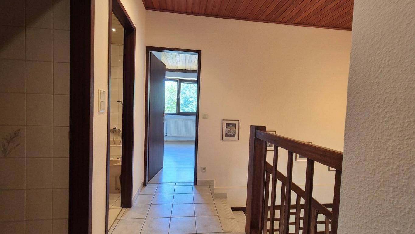 Heller Flur im Obergeschoss mit Fliesenboden und Blick in ein angrenzendes Zimmer.