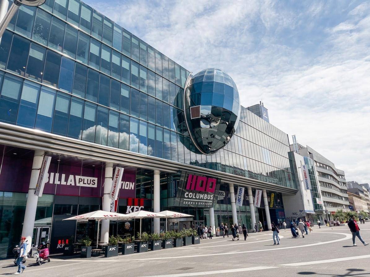 Modernes Einkaufszentrum mit Glasfassade und Außengastronomie.