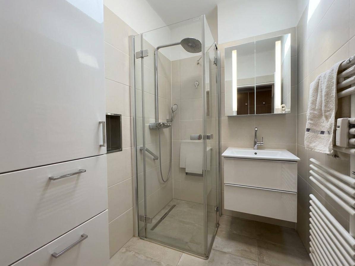 Modernes Badezimmer mit Duschkabine, Waschbecken und beheiztem Handtuchhalter.