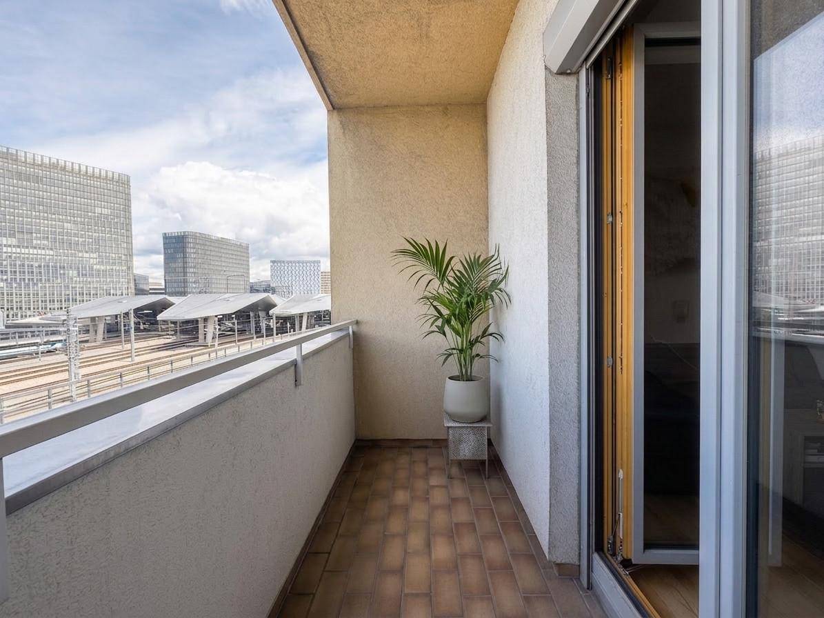 Schmaler Balkon mit Fliesenboden, einer Pflanze und Blick auf die Stadt.