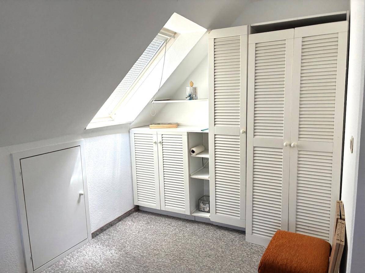 Praktischer Stauraum im Dachgeschoss mit Einbauschränken und einem Dachfenster für Licht.