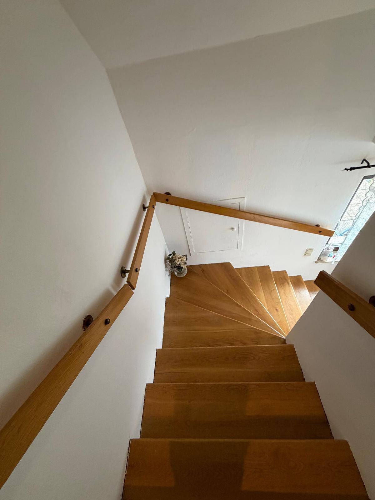 Holztreppe mit Holzgeländer führt in die oberen Stockwerke des Hauses.