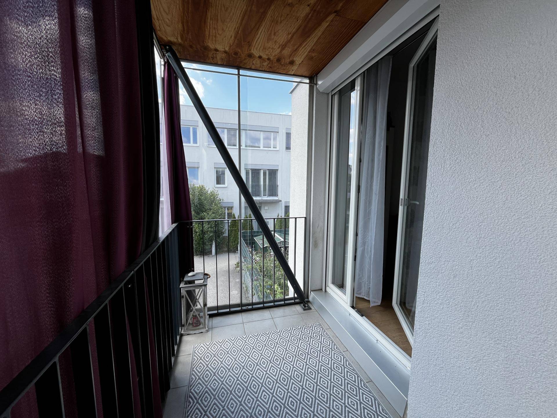 Heller verglaster Balkon mit Fliesenboden und Zugang zum Innenbereich der Wohnung.