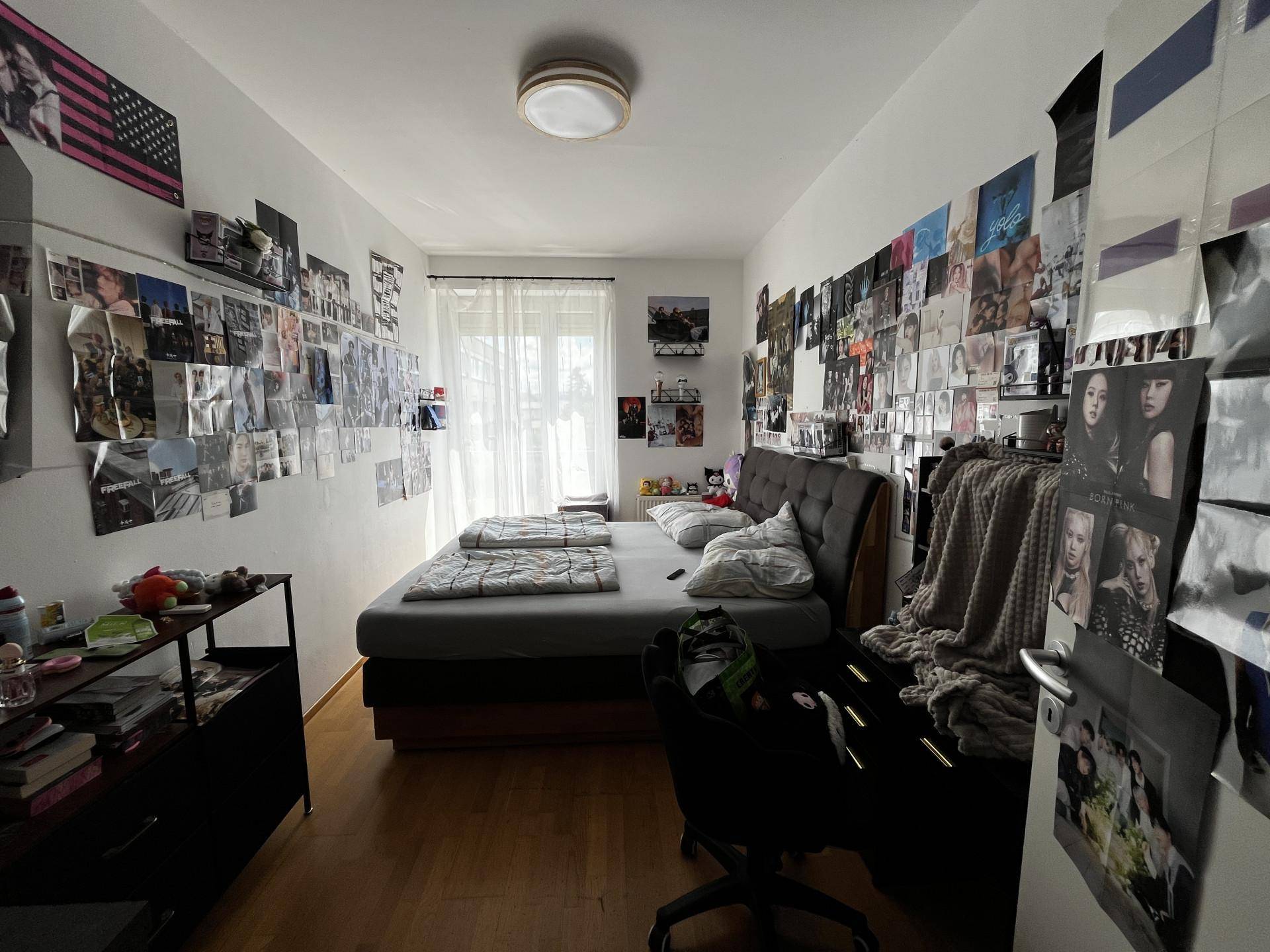 Schlafzimmer mit Bett, Schreibtisch und Wänden, die mit Postern dekoriert sind.