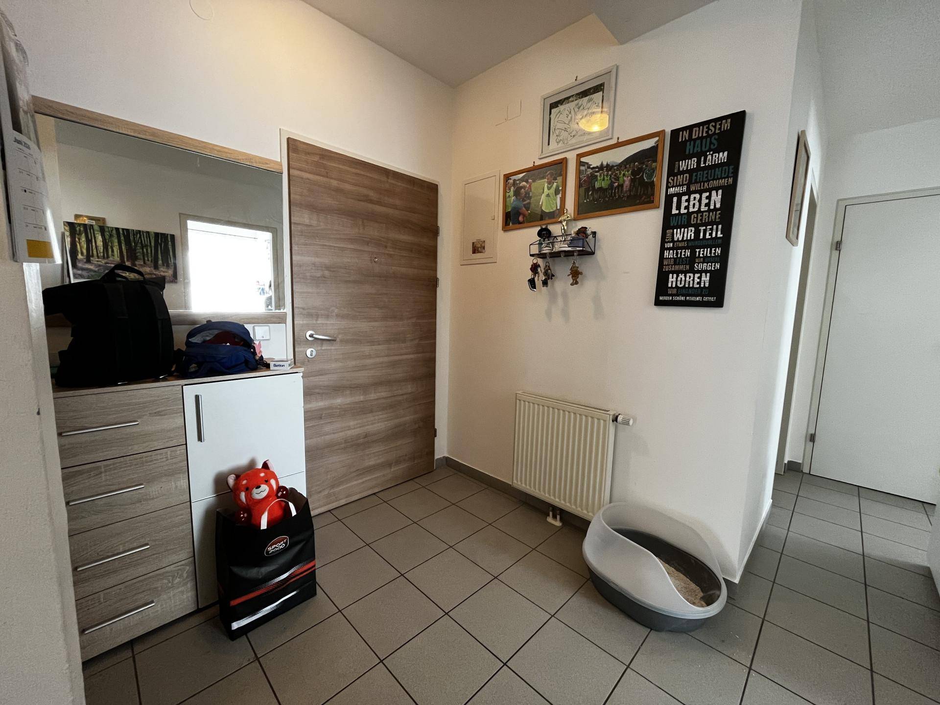 Eingangsbereich mit Fliesenboden, Schuhschrank und Spiegel an der Wand.
