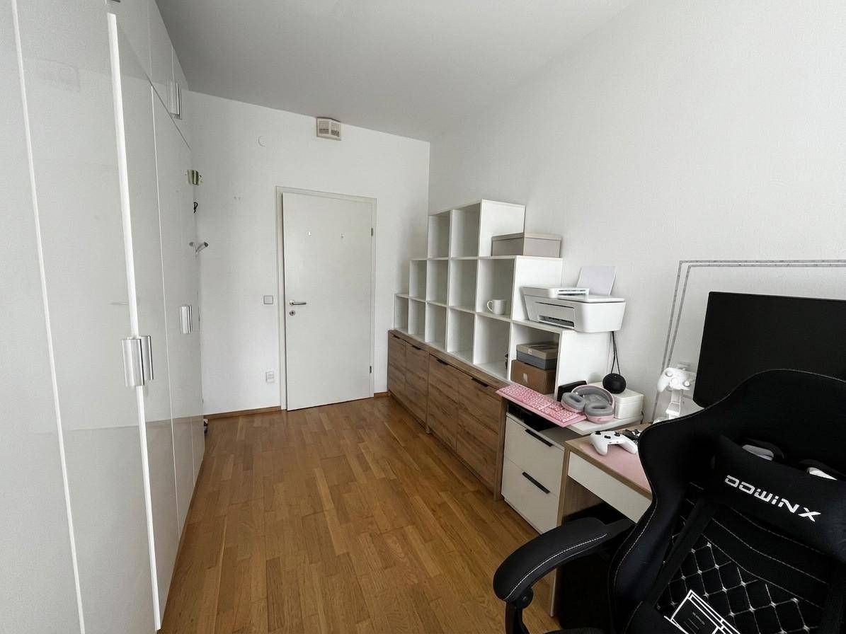 Zimmer mit weißen Kleiderschränken, Schreibtisch und Holzfußboden.