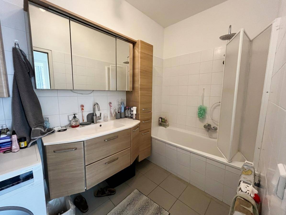 Badezimmer mit Badewanne, Waschbecken, Spiegelschrank und Waschmaschine.