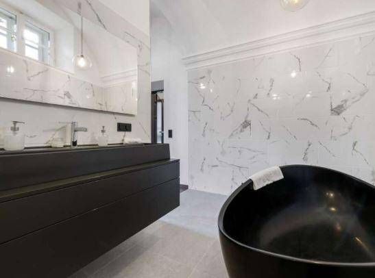 Modernes Badezimmer mit freistehender schwarzer Badewanne und großem Spiegel über dem Doppelwaschbecken.