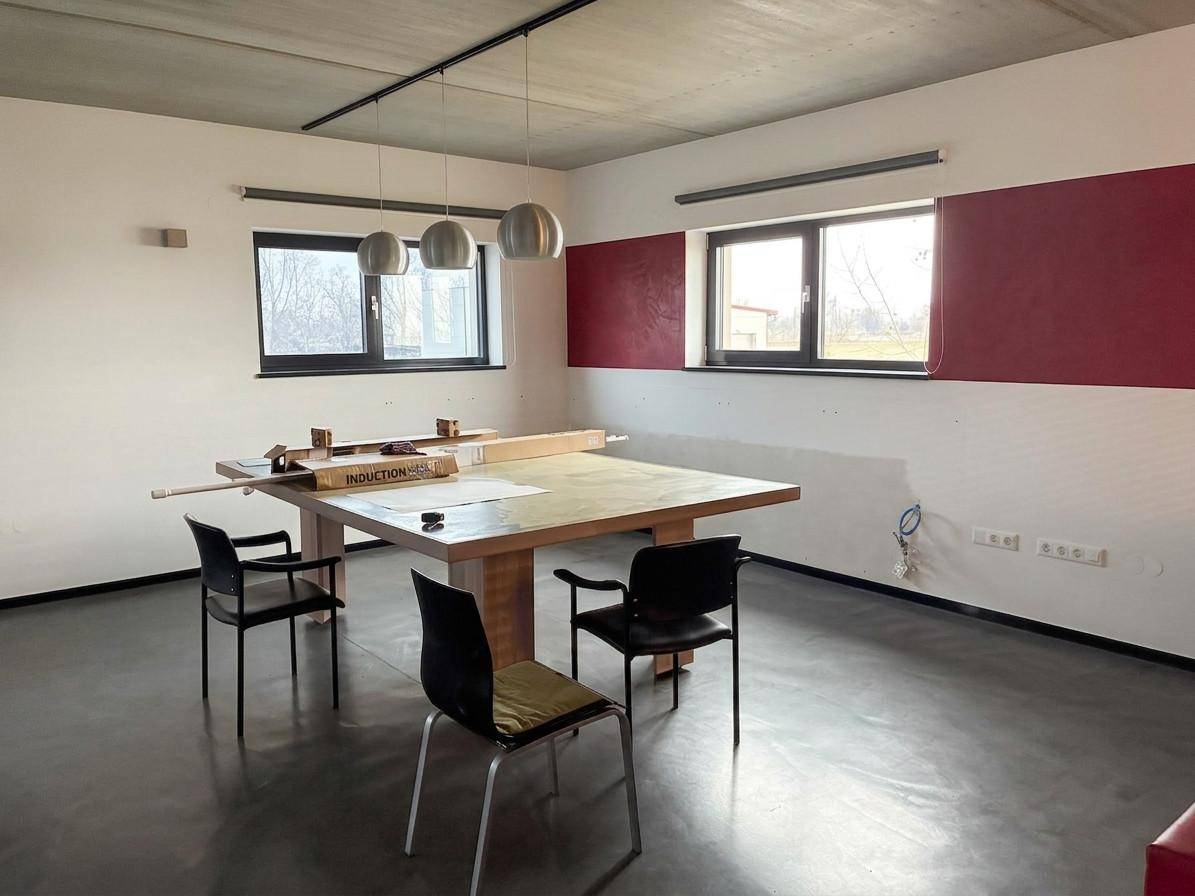 Geräumiger Essbereich mit großem Holztisch, modernen Hängelampen und einem polierten Betonboden.