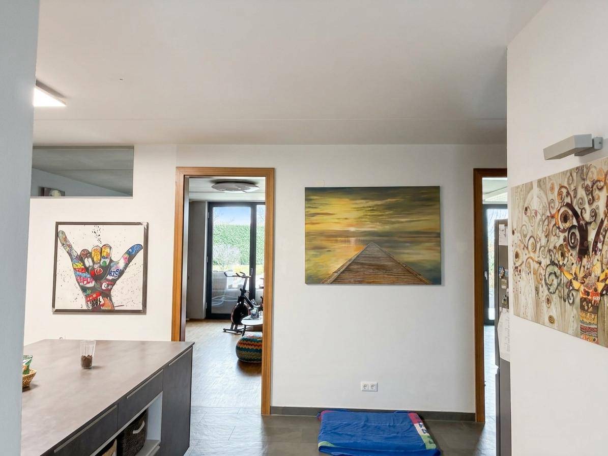 Heller Innenbereich mit modernen Kunstwerken an den Wänden und einem Blick in angrenzende Räume.