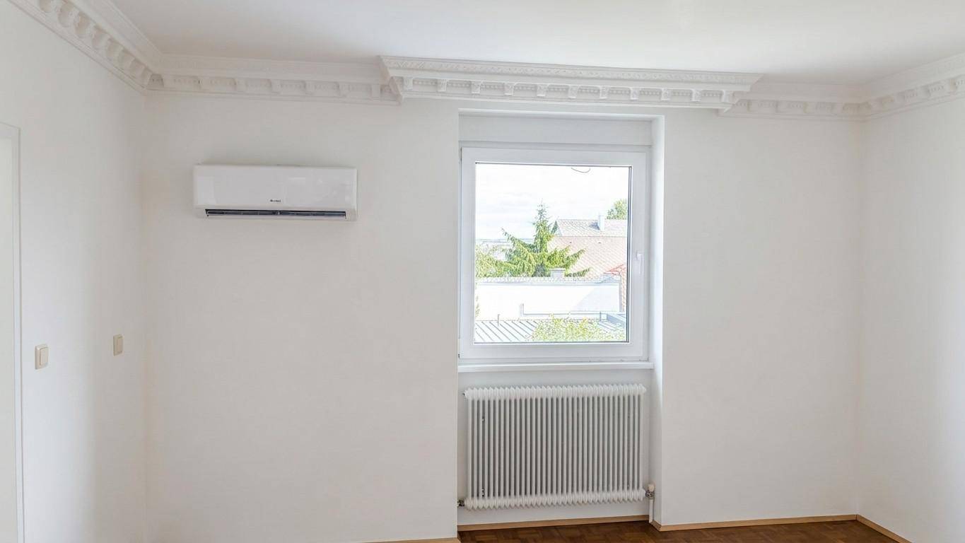 Heller Raum mit Fenster, Heizkörper, Klimaanlage und dekorativer Stuckdecke.