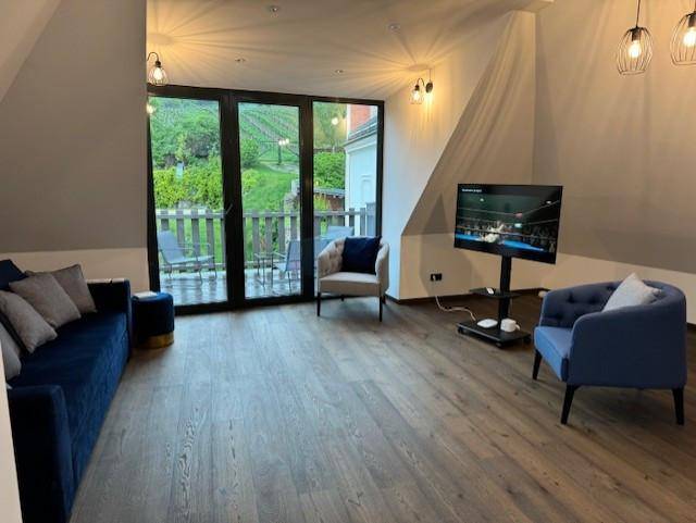 Heller Wohnbereich mit bequemen Sofas, Fernseher und Zugang zu einem Balkon.