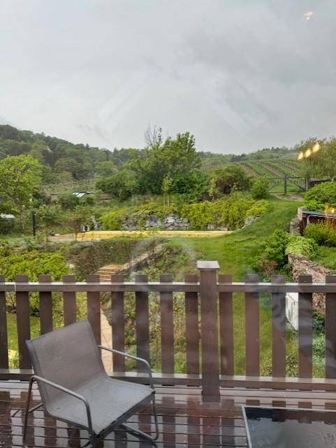 Balkon mit Sitzgelegenheit und weitem Blick auf grüne Weinberge und Hügel.