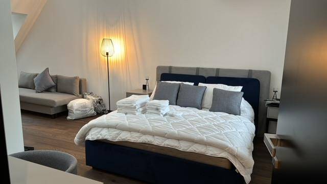 Gemütliches Schlafzimmer im Dachgeschoss mit Doppelbett, Sofa und Holzboden.
