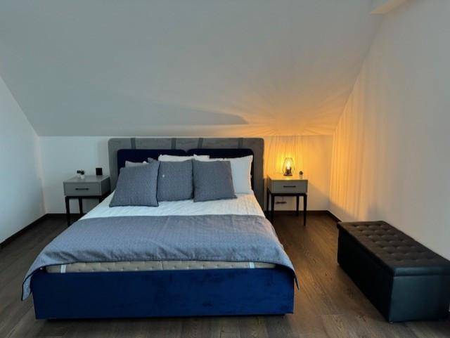 Helles Schlafzimmer im Dachgeschoss mit Doppelbett, Nachttischen und Holzboden.