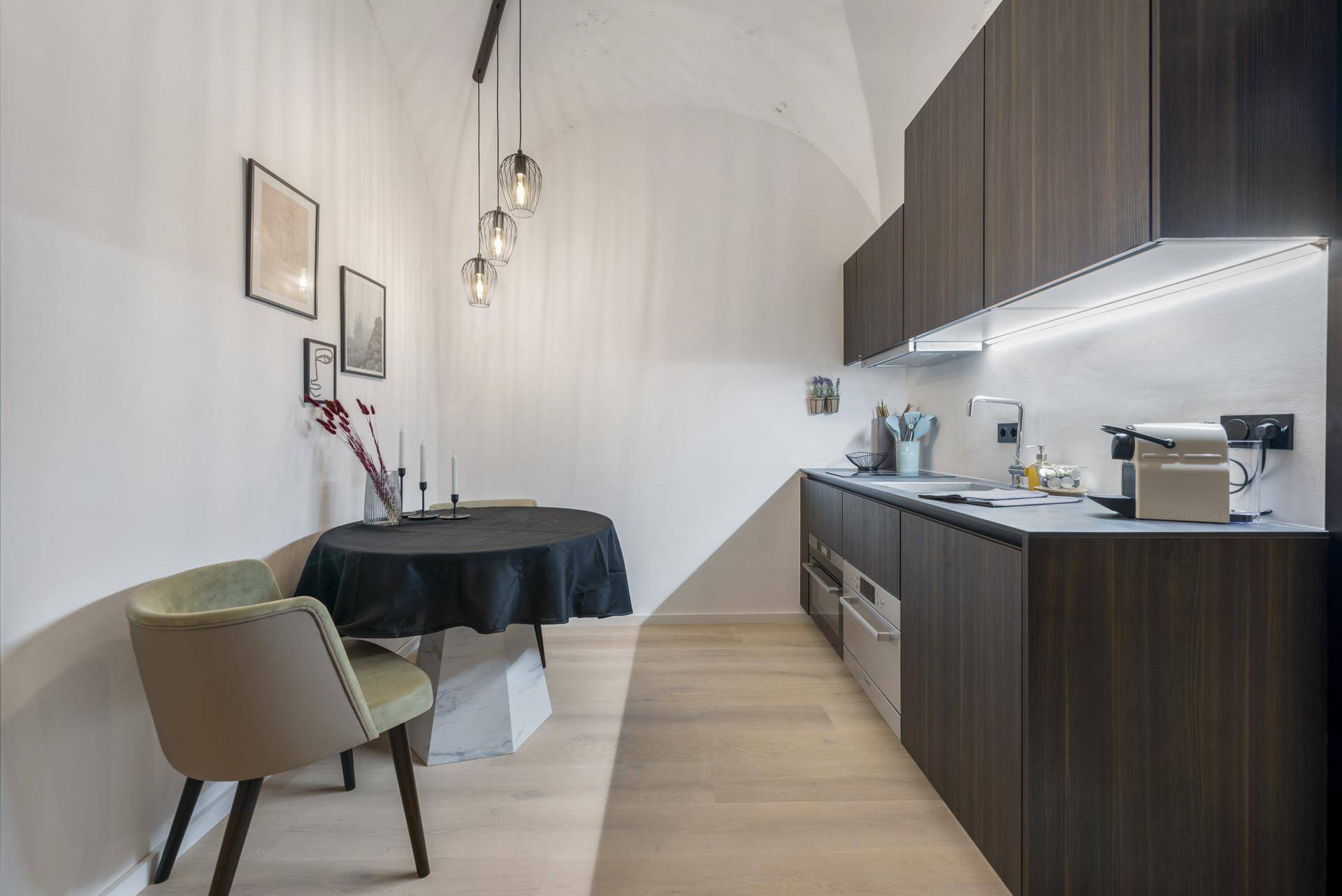 Moderne Küche mit dunklen Holzfronten, integrierten Geräten und kleinem Essbereich.