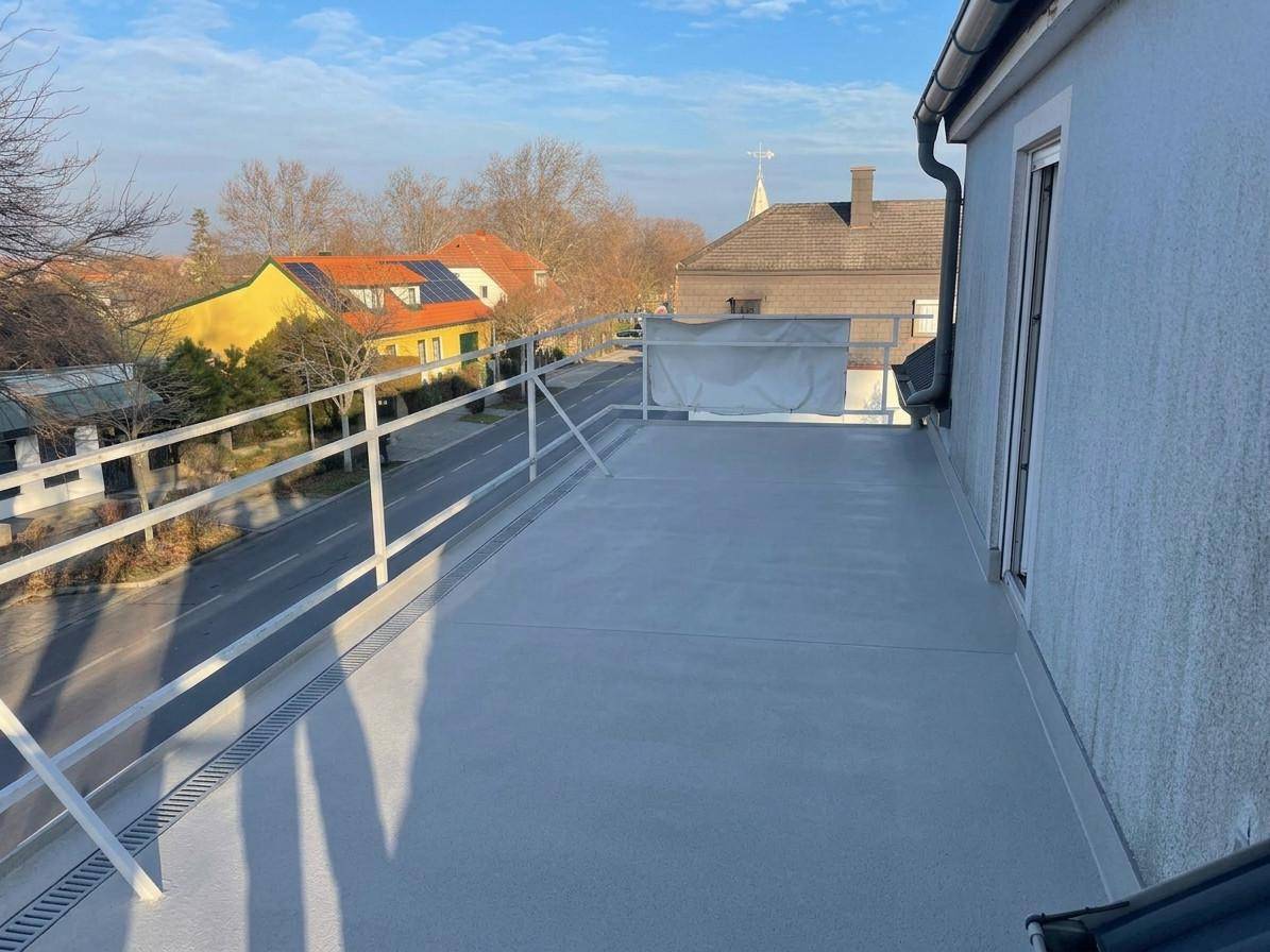 Große Dachterrasse mit hellem Bodenbelag und Blick auf die Nachbarschaft.