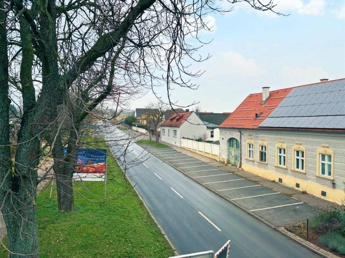 Blick auf die ruhige Wohnstraße mit parkenden Autos und umliegenden Häusern.