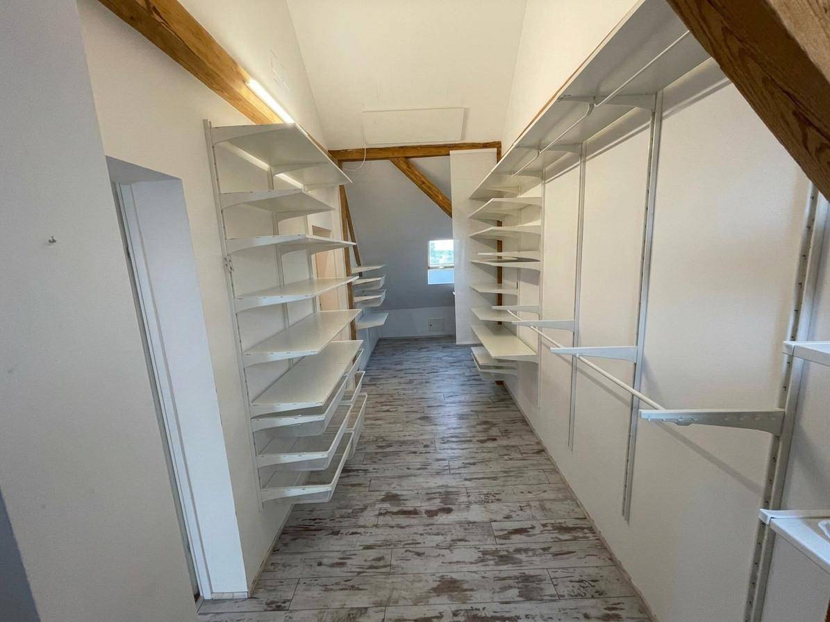 Heller Dachbodenraum mit sichtbaren Holzbalken und praktischen Regalsystemen.