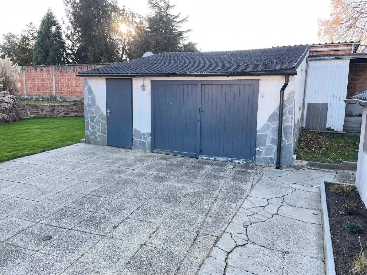 Freistehende Garage mit gepflastertem Vorplatz und Zugang zum Gartenbereich.