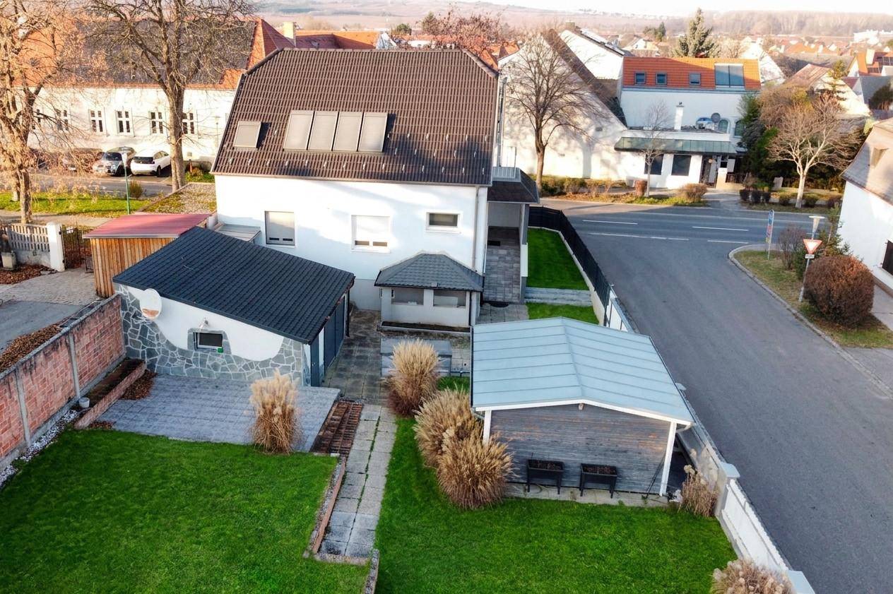 Luftaufnahme des Anwesens mit Haus, Nebengebäuden, Garten und umliegender Bebauung.