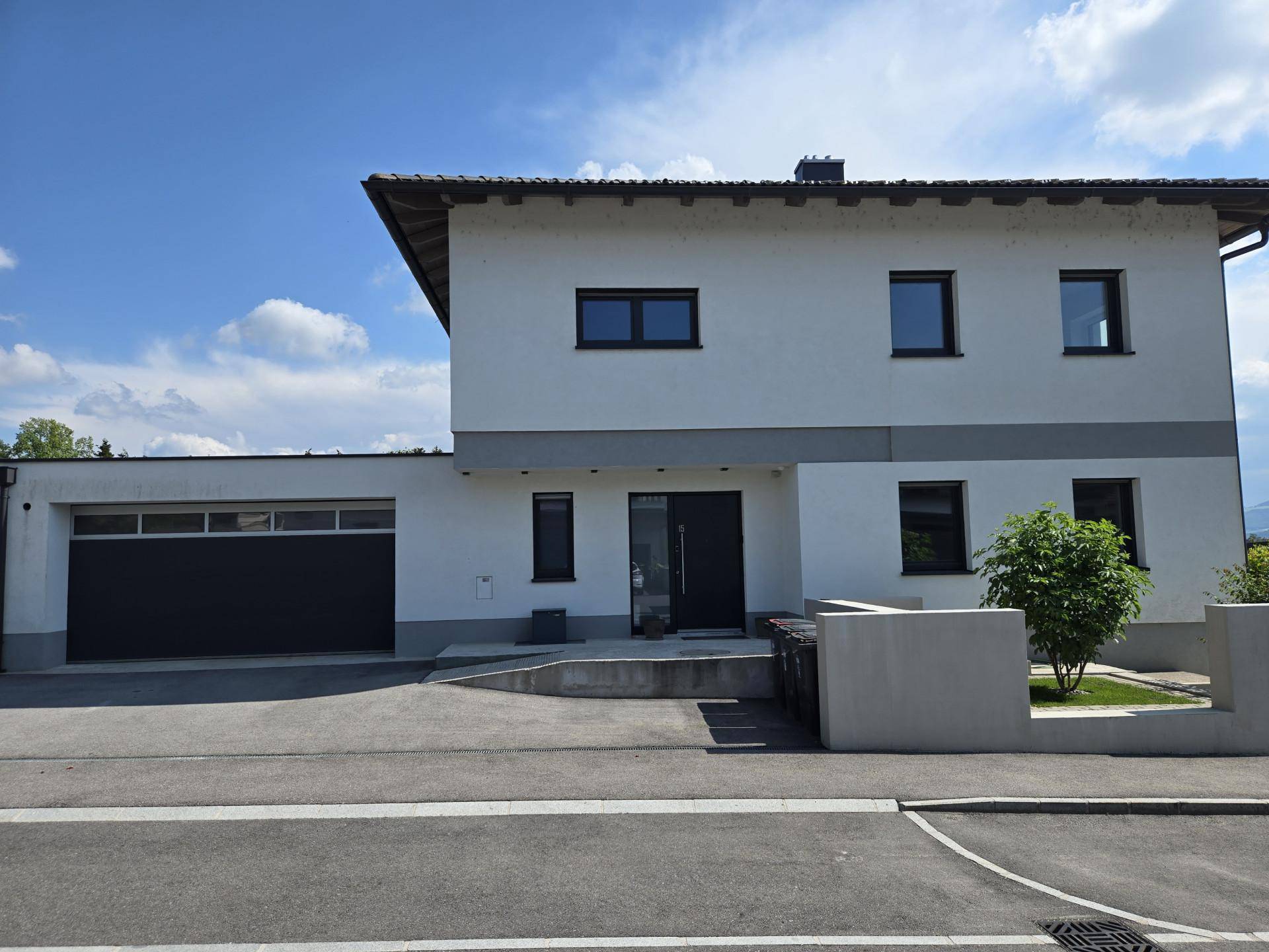 Frontansicht des modernen Einfamilienhauses mit Garage und gepflegtem Vorgarten.
