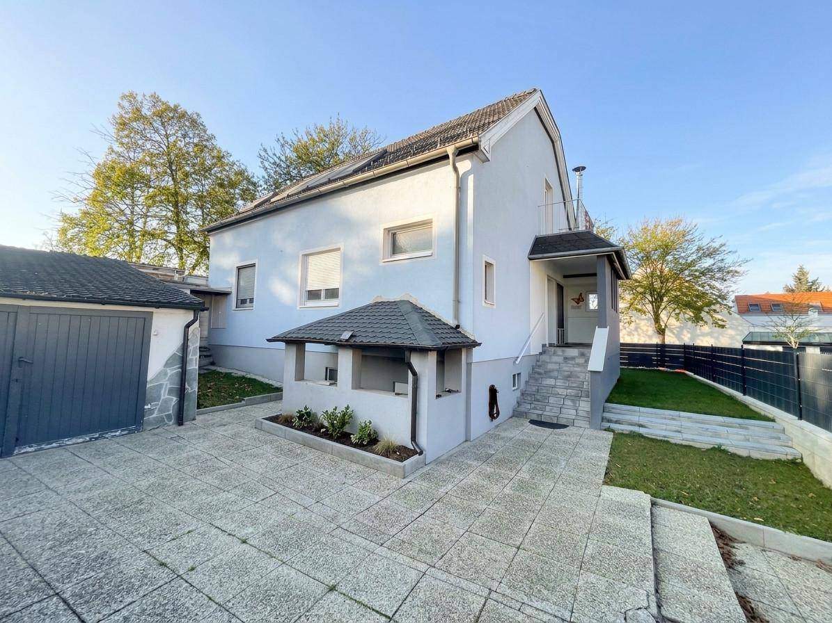 Ansicht des Hauses von vorne mit Garage, gepflasterter Einfahrt und Vorgarten.
