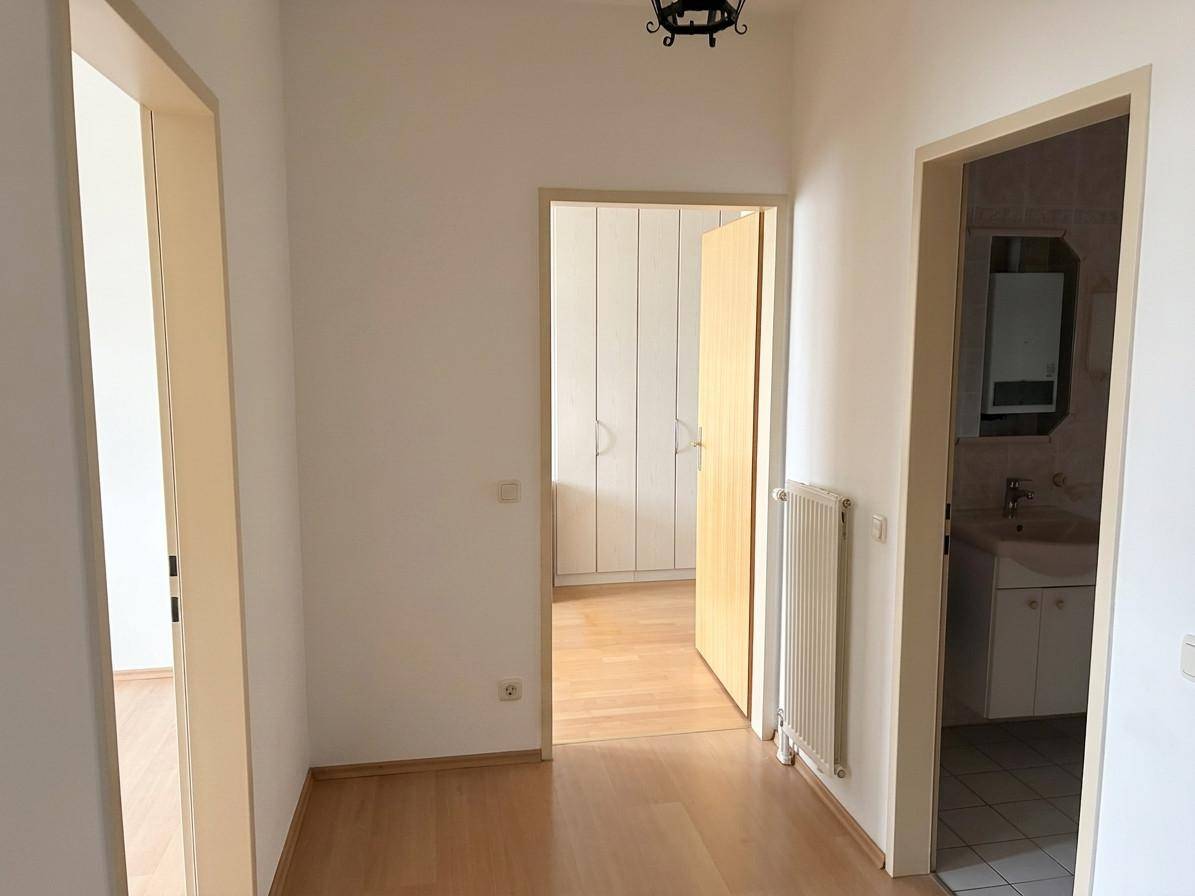 Heller Flur mit mehreren Türen, Heizkörper und Blick in ein angrenzendes Badezimmer.